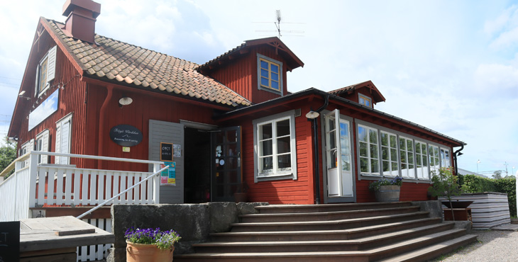 Frösjö Wärdshus röda hus med svarta detaljer. Framför huset syns en stor altan. 
