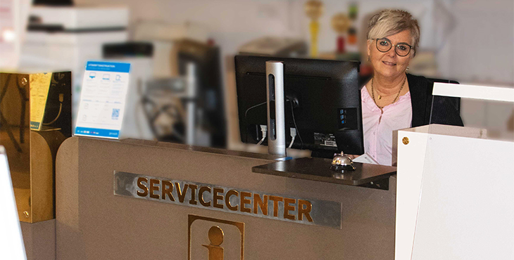 en kvinna i glasögon som står bakom servicecenters informationsdisk