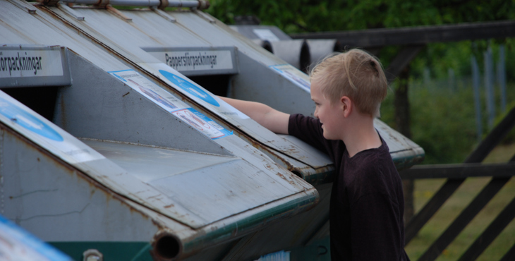 Pojke vid återvinningscontainer