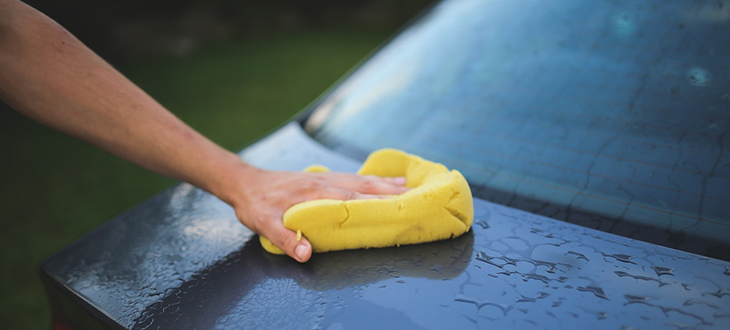 hand med tvättsvamp som tvättare en bil