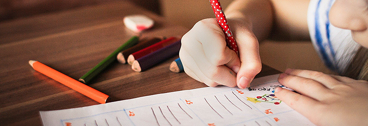 Barnhand som skriver i ett anteckningsblock